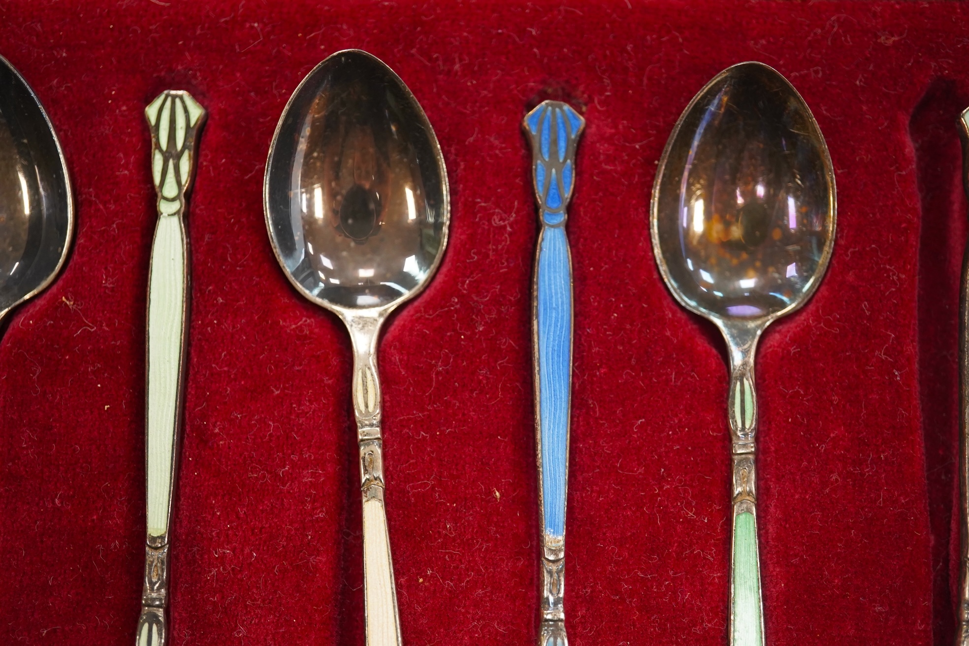 A set of six silver grapefruit spoons, Cooper Brothers & Sons, Sheffield, 1936, a modern pair of silver mounted dwarf candlesticks, a silver egg cup and spoon and a set of six silver gilt and enamelled coffee spoons, all
